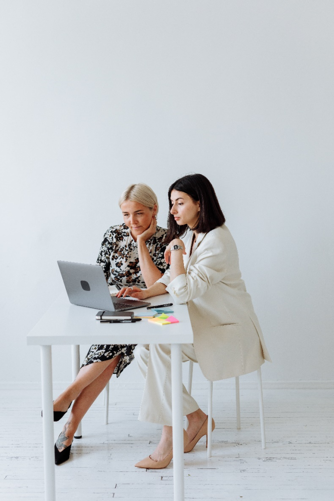 Two women in chic clothing sitting and discussing something.