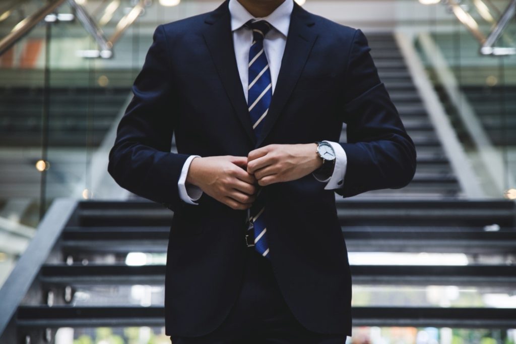 A person dressed in a professional suit, wearing a watch. 